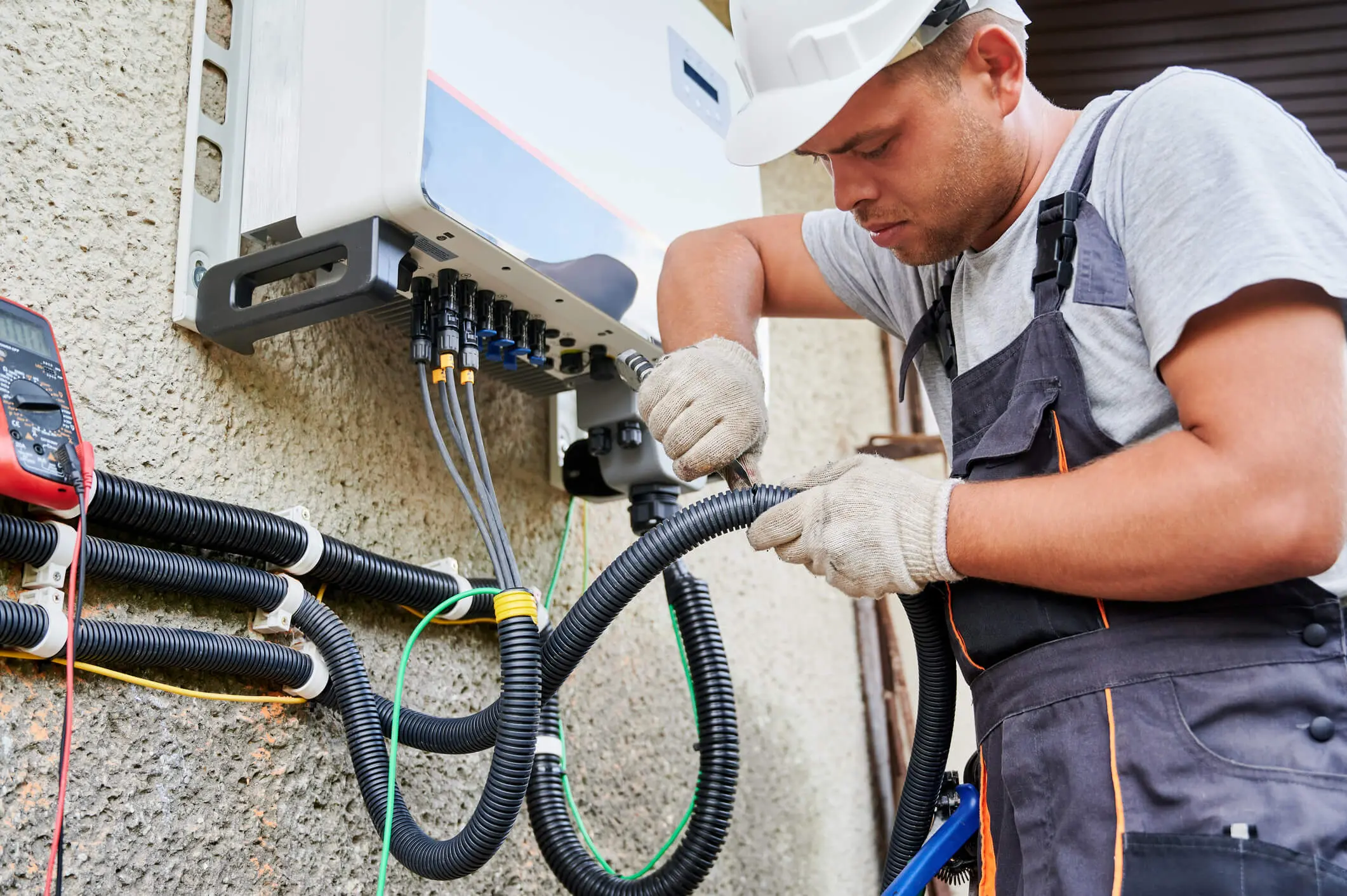 Technician inspecting and repairing electrical cables outdoors.