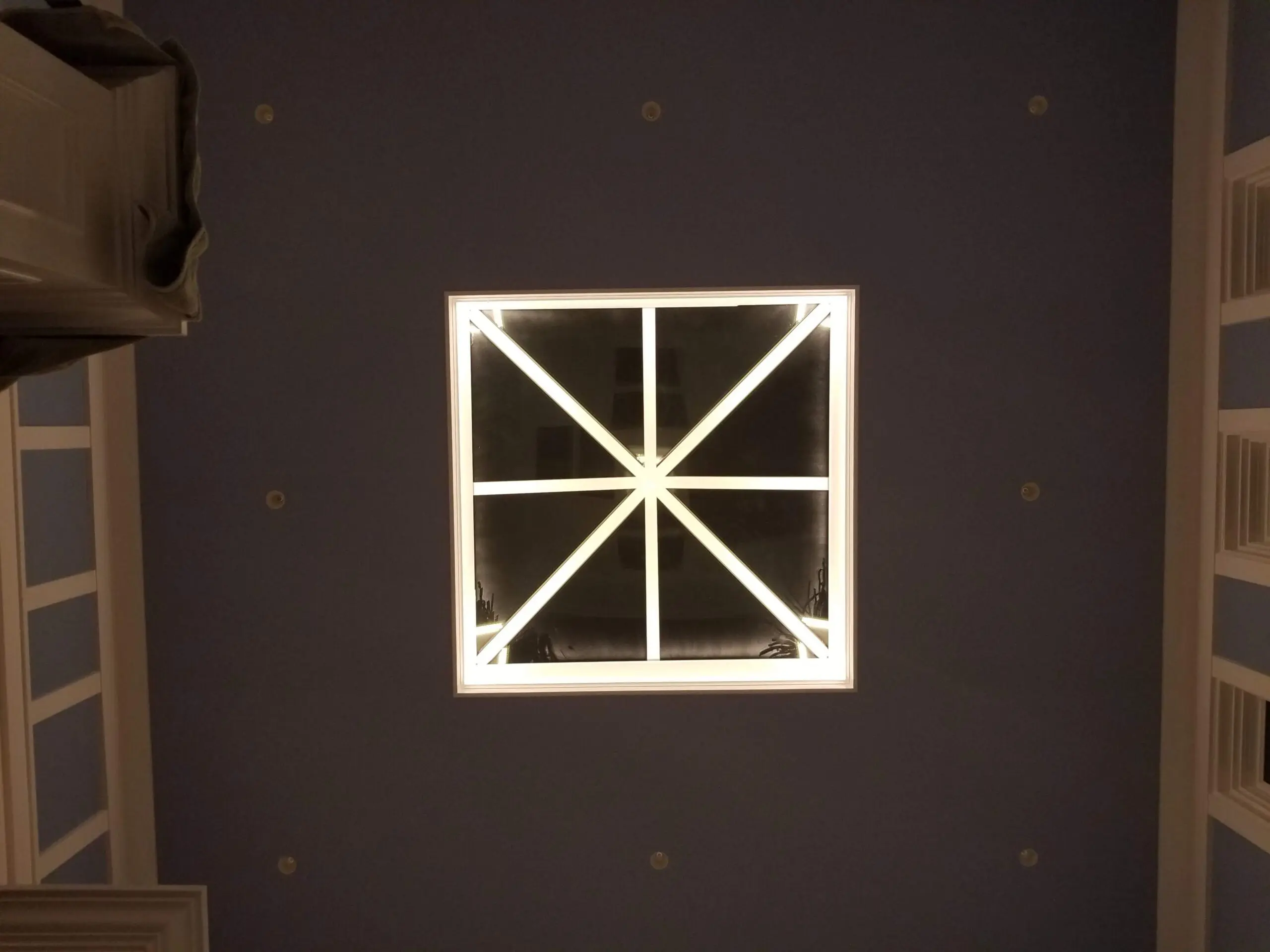 Illuminated square ceiling light with geometric design.