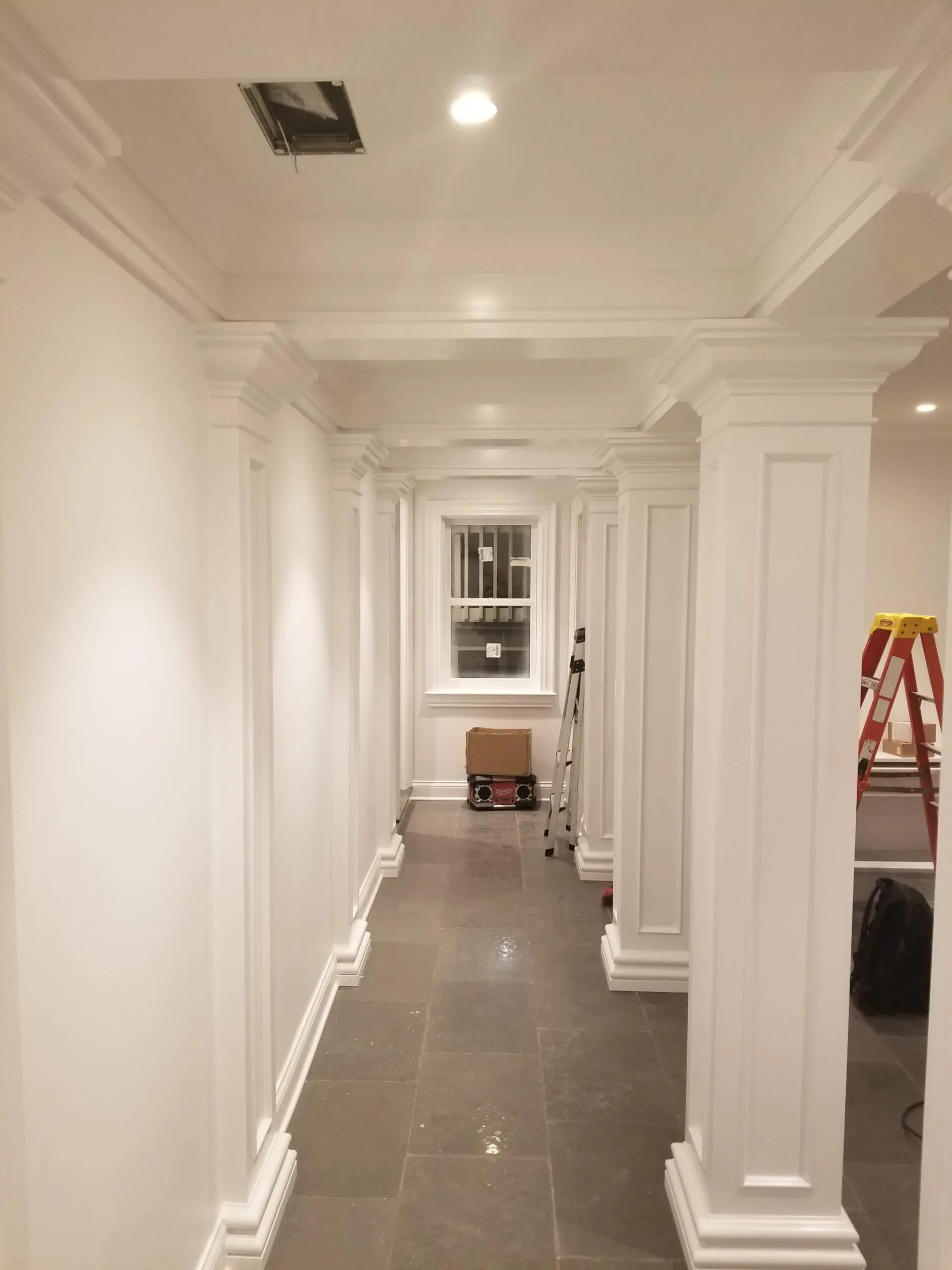 A renovated hallway with white walls and columns.
