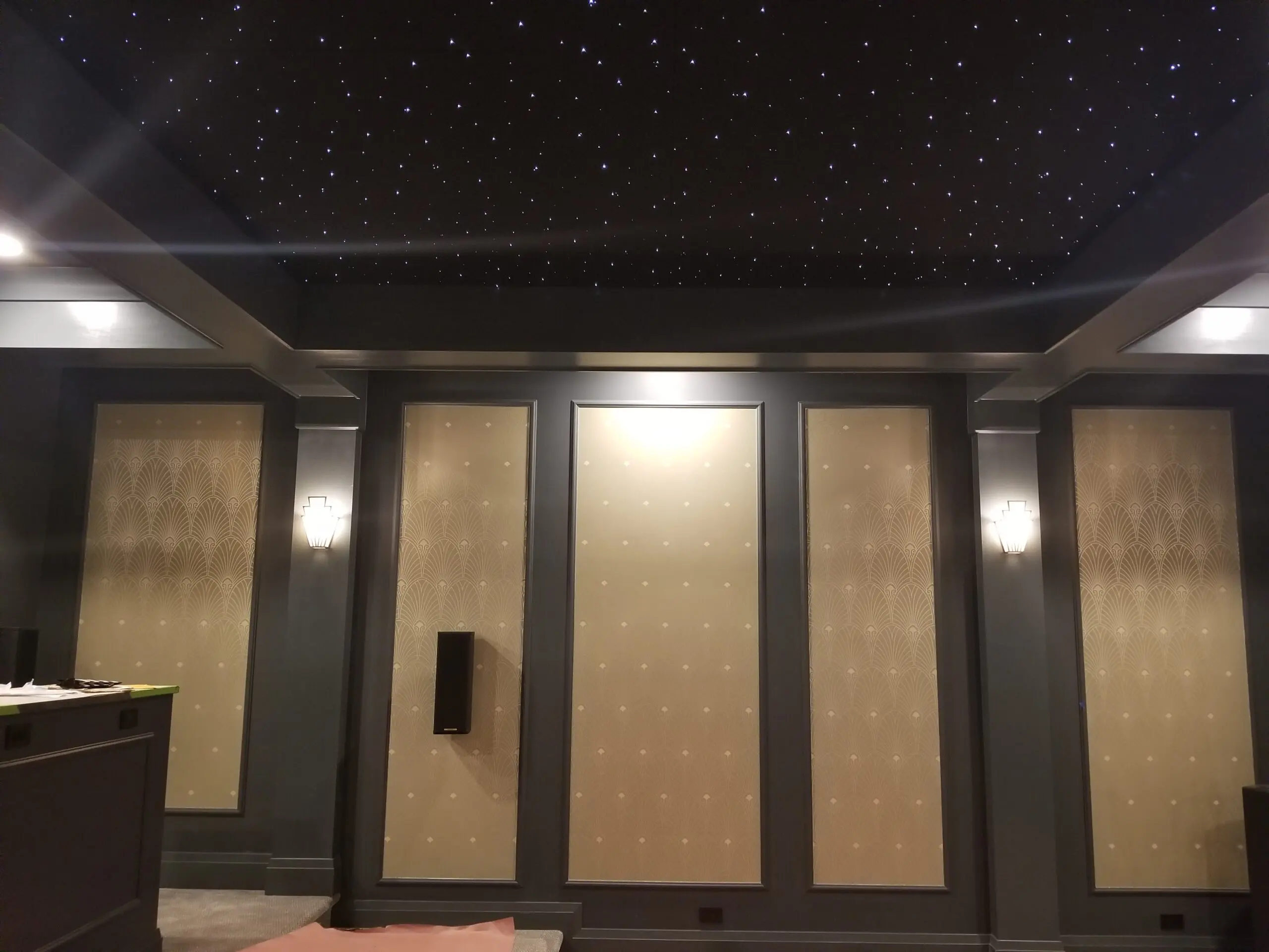 Elegant indoor ceiling with star-like lights and warm wall sconces.