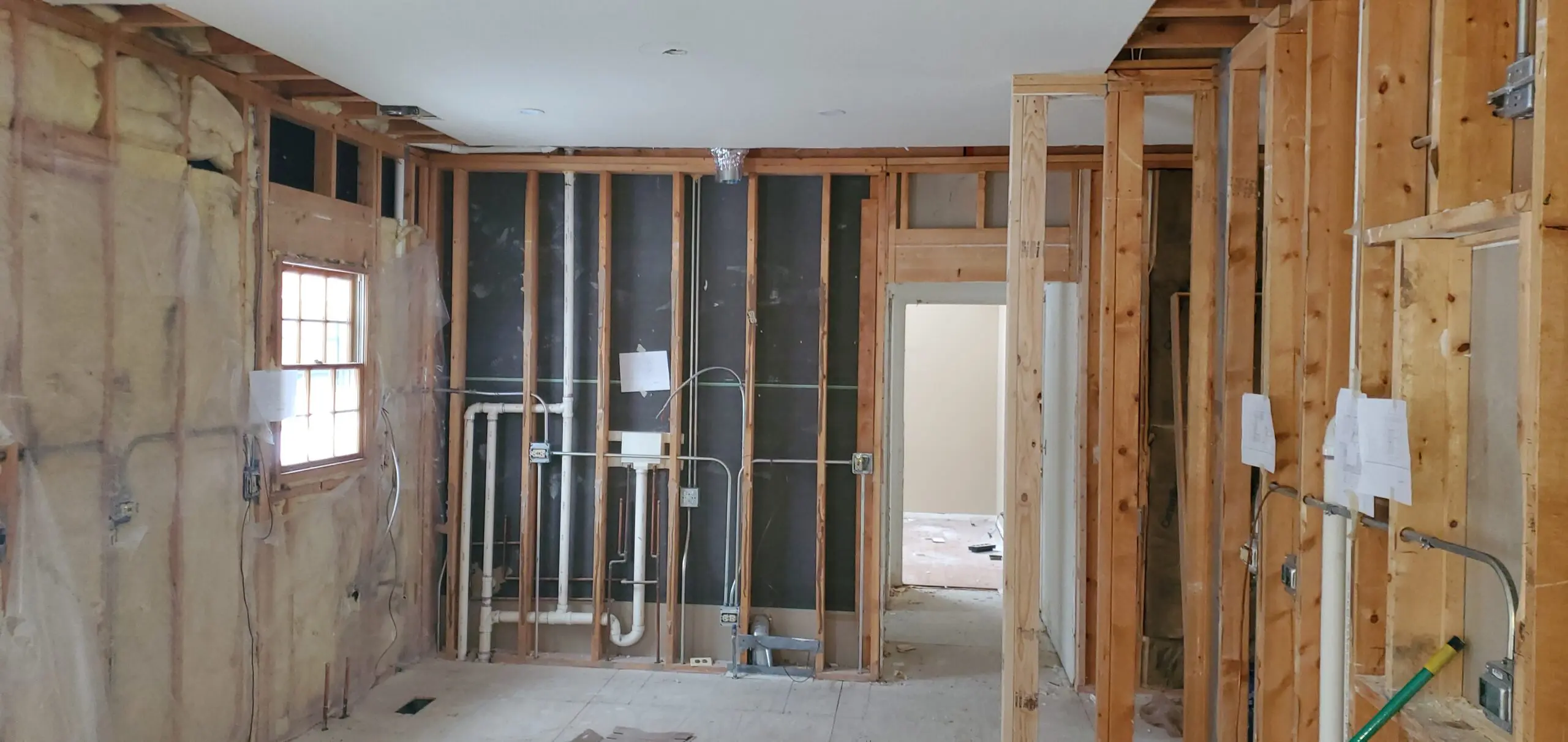 Partially framed interior wall with exposed plumbing and wiring.
