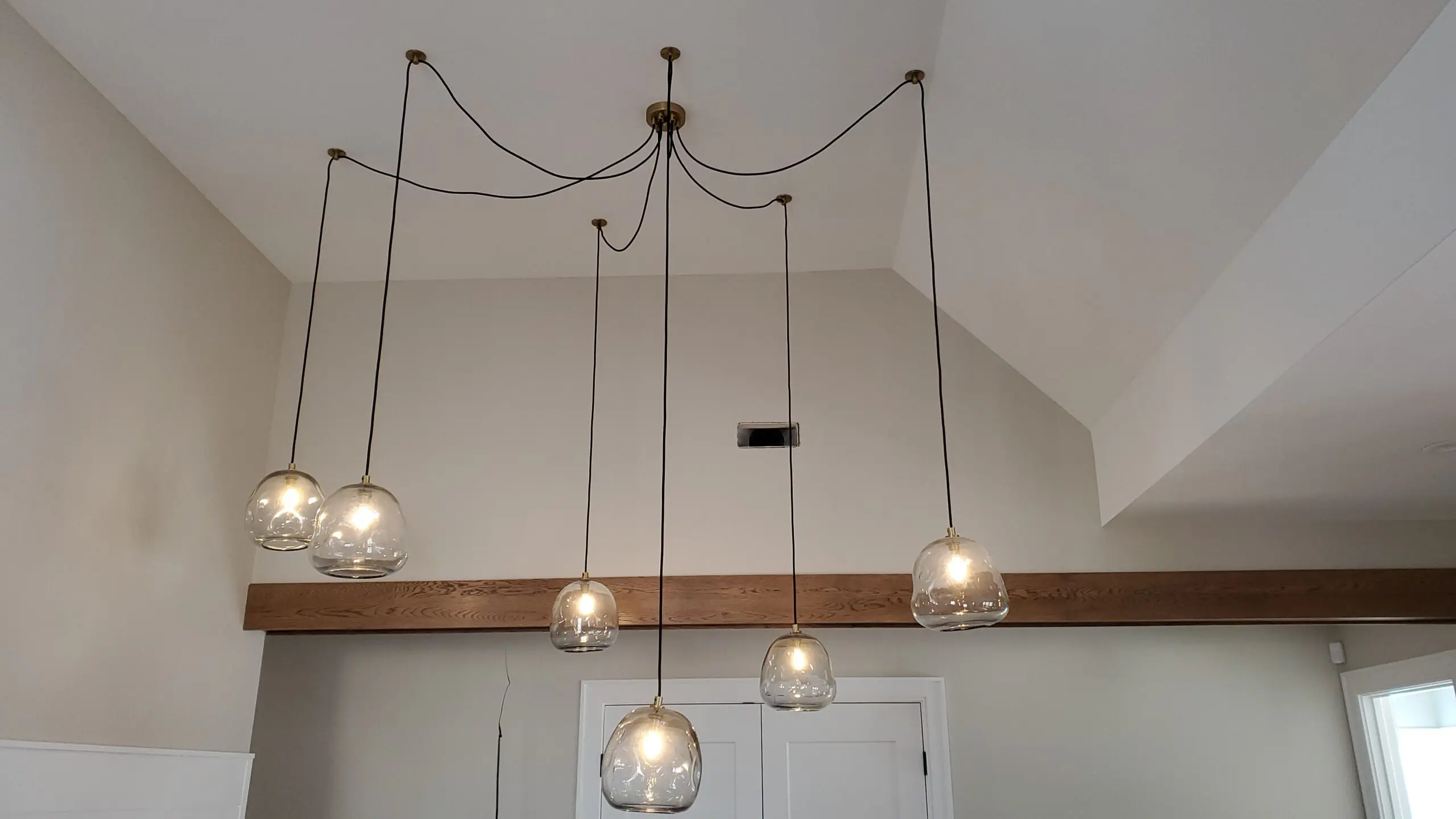 Modern hanging light fixtures with glass globes in a dining area.