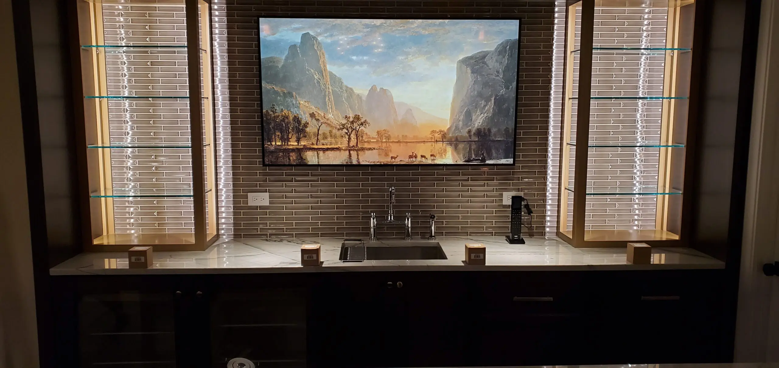 A kitchen sink area with a large landscape painting above it.