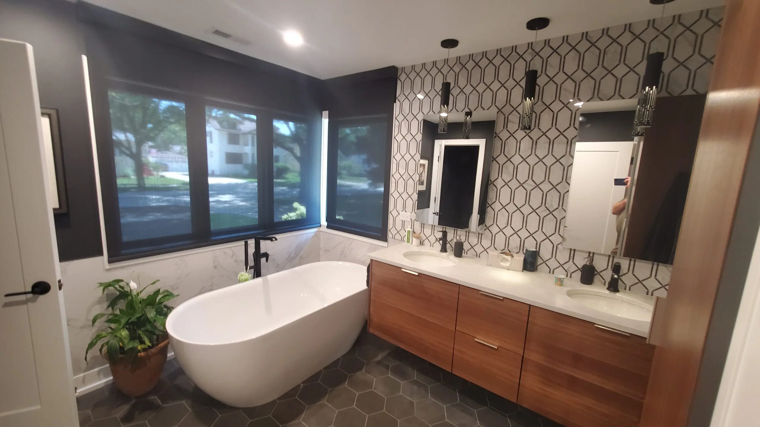 Modern bathroom with freestanding tub and geometric patterned wall.