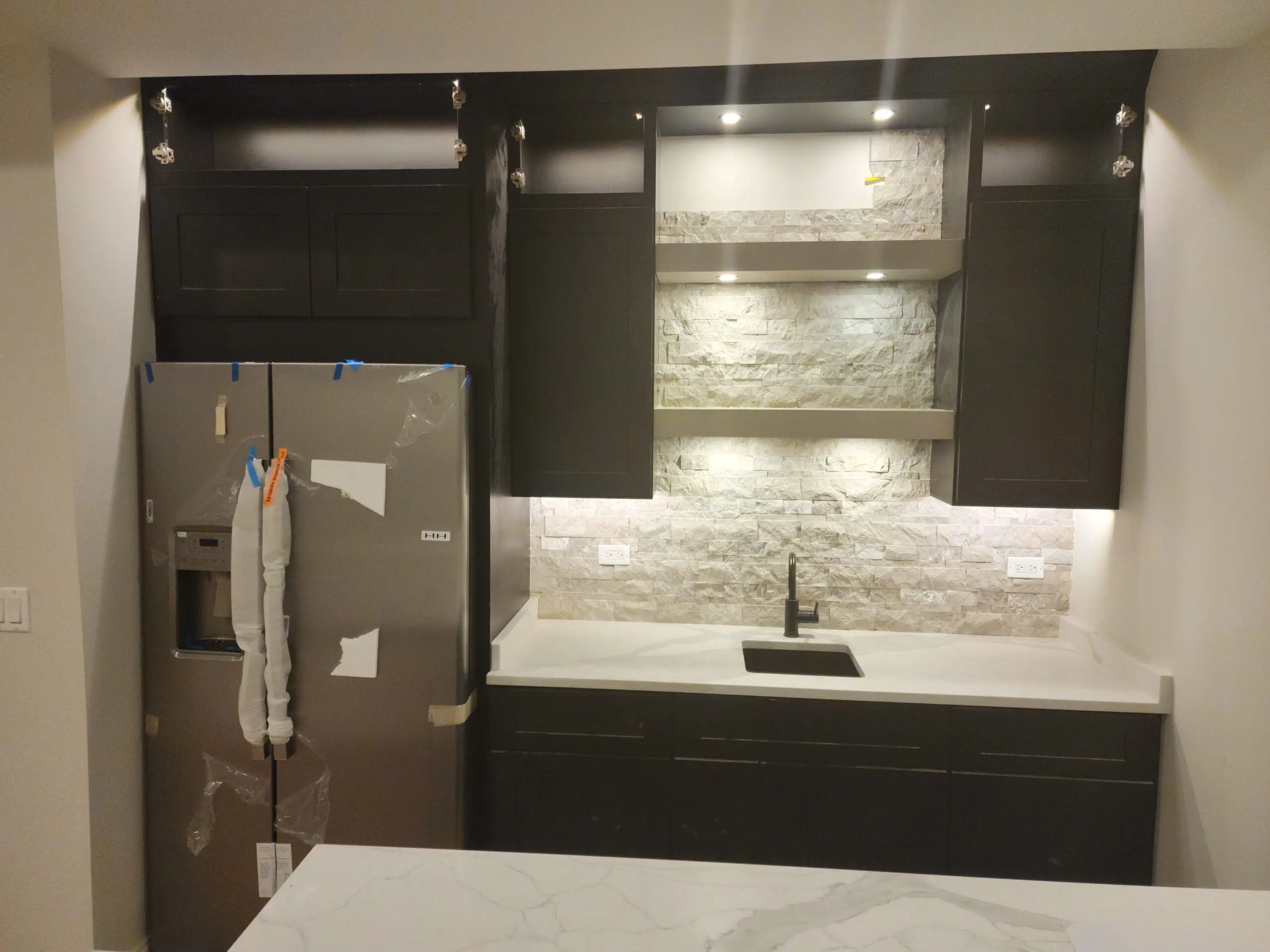 Modern kitchen with stone backsplash and black fixtures.