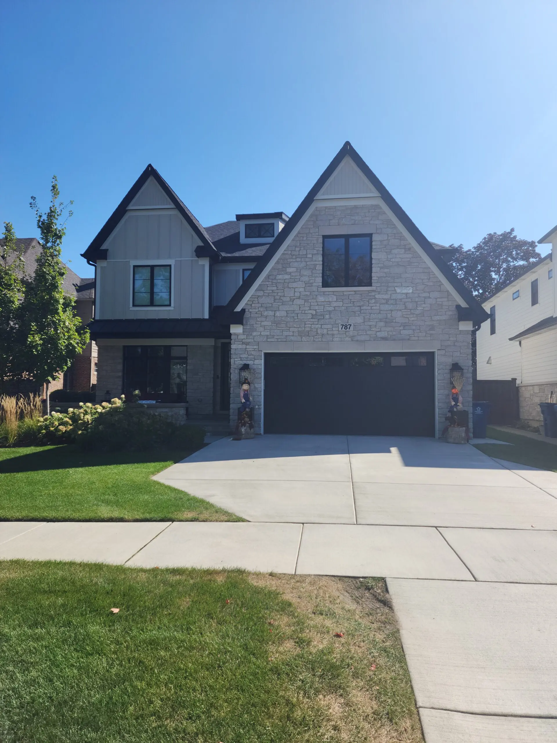 Modern two-story house with stone and siding exterior and a spacious driveway.