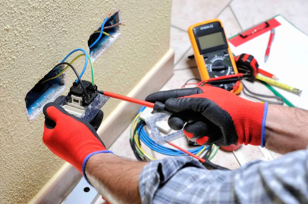 Electrician testing a power outlet with a multimeter.