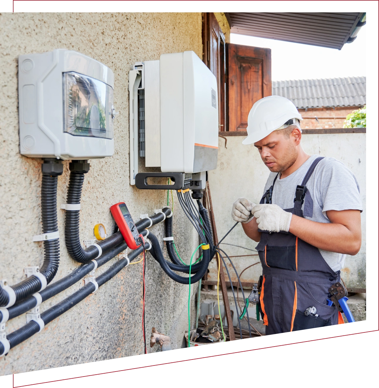 Technician inspecting outdoor electrical equipment on a building wall.