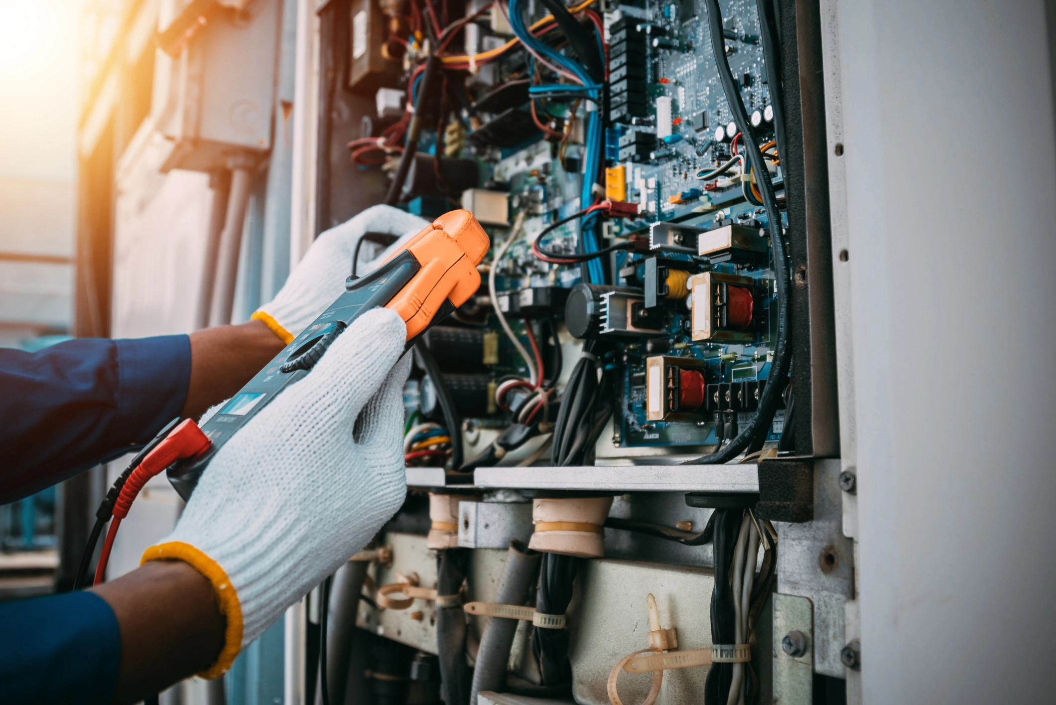 Technician repairs electrical circuit inside a panel.