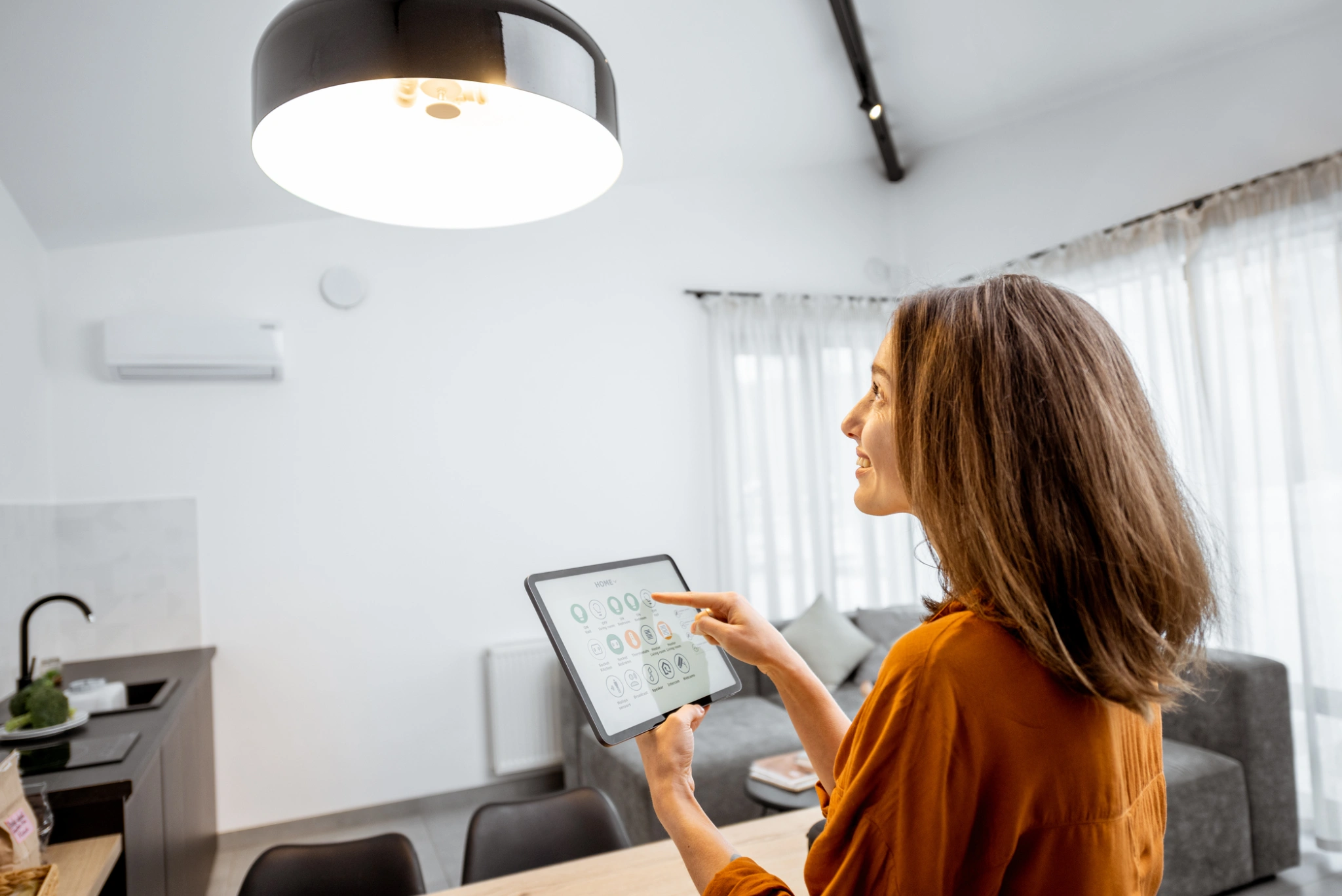 Woman using a tablet in a well-lit room with modern decor.
